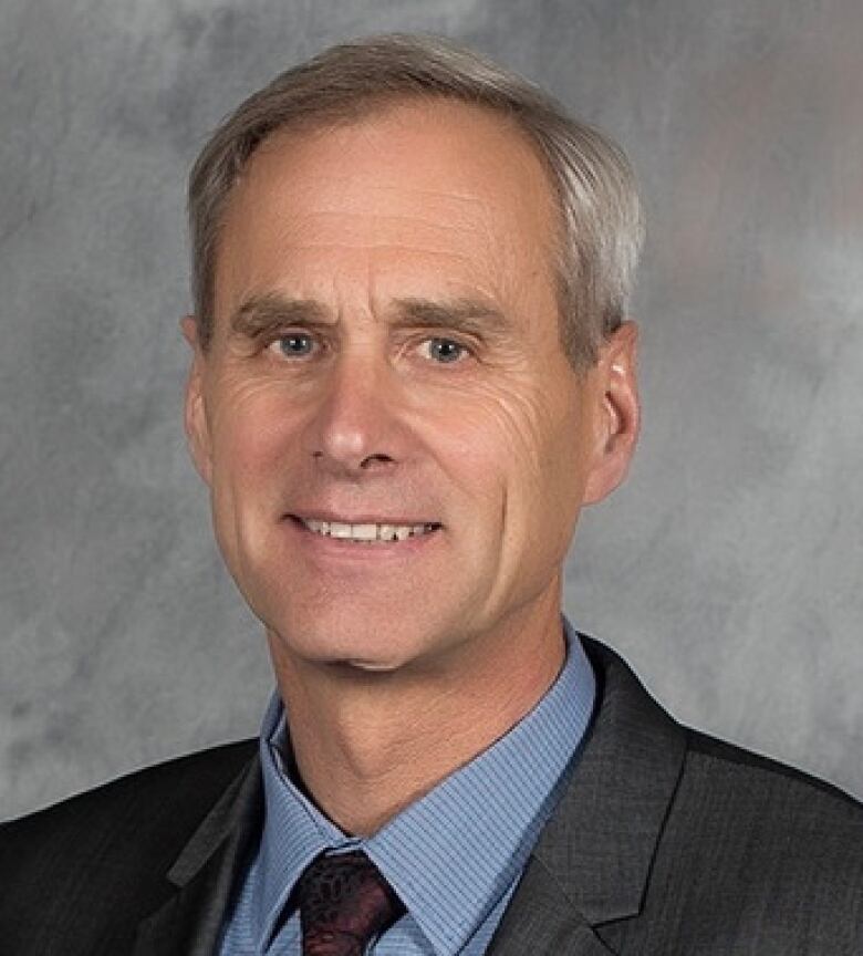 A headshot of a man in a suit. 