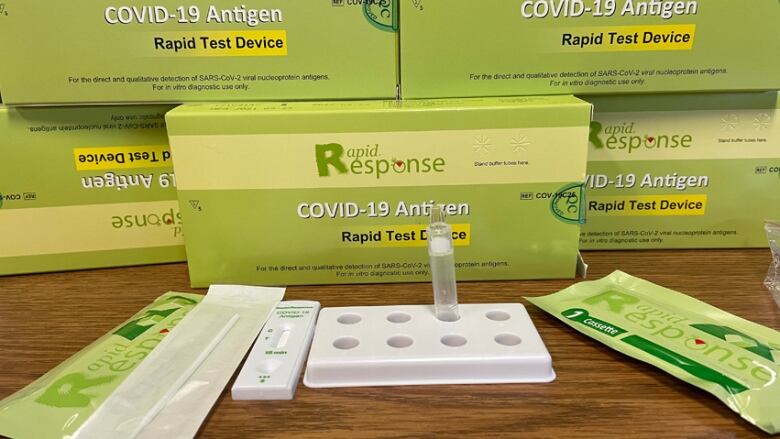 Several boxes of COVID-19 rapid test kits and the contents of a box on display.