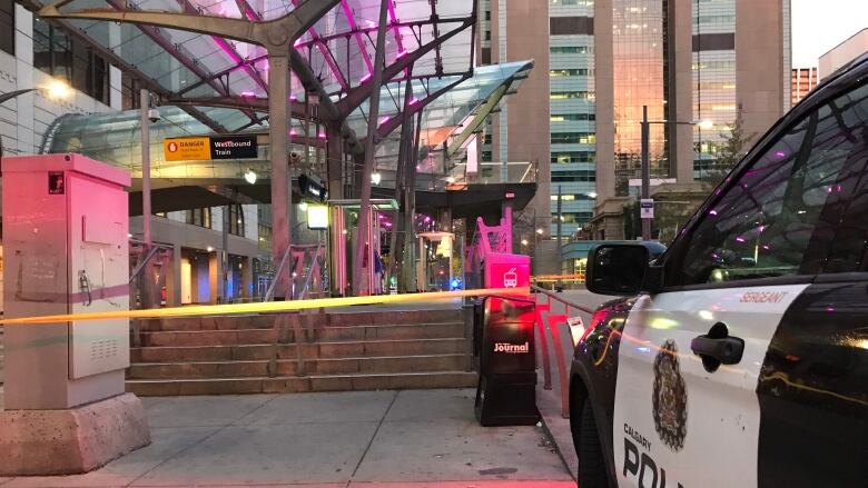 A police car is parked outside a taped-off area of a CTrain platform. 