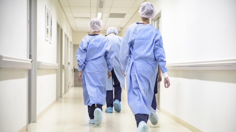 Nurses walking down a hospital corridor seen from the back.