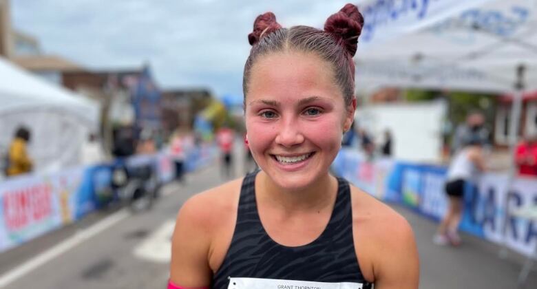 A white woman with her hair in two buns is wearing a running top