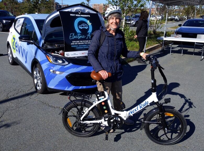 A white woman wearing a helmet behind a bicycle