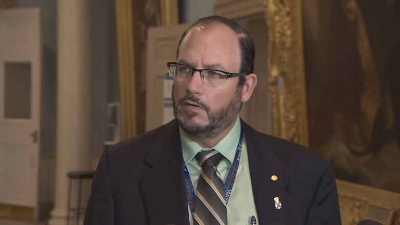 A white man wearing glasses and a suit