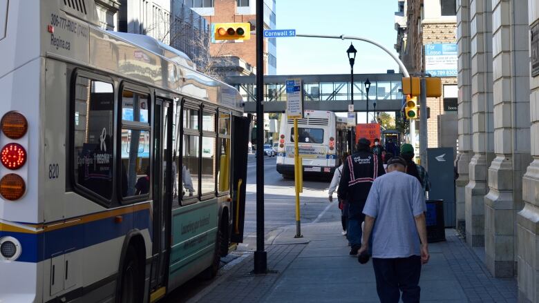 A group of people walk beside a Regina Transit bus on 11th Avenue in Regina, Sask. 