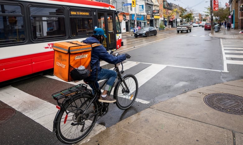 A person on a bike next to a streetcar, they are not in a bike lane.