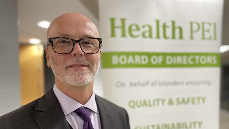 Bearded man with glasses in front of Health P.E.I. sign. 