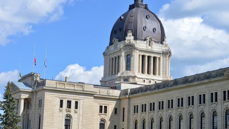 A stone, domed legislative building is shown in front of a blue sky.