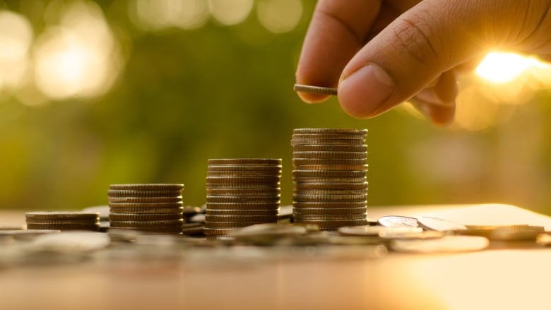 A hand stacking coins.