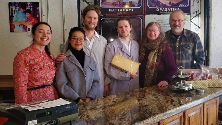 A group of people standing behind a cheese counter.