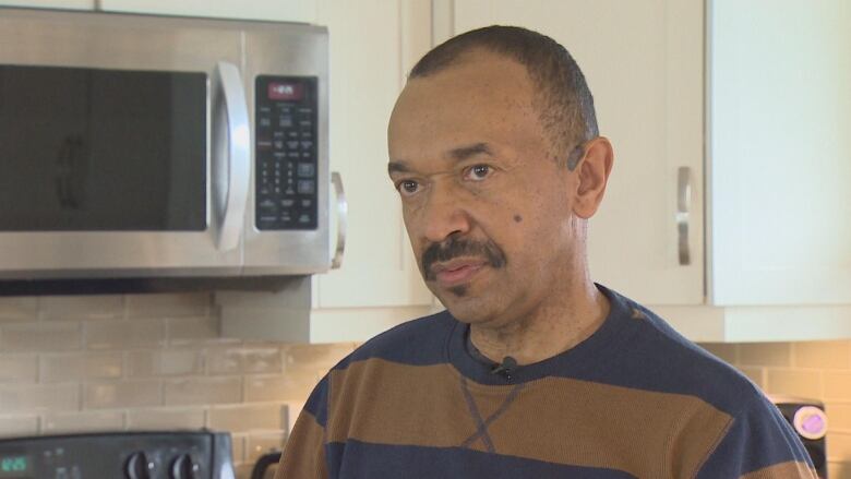 A Black man with a mustache wearing a stripped shirt