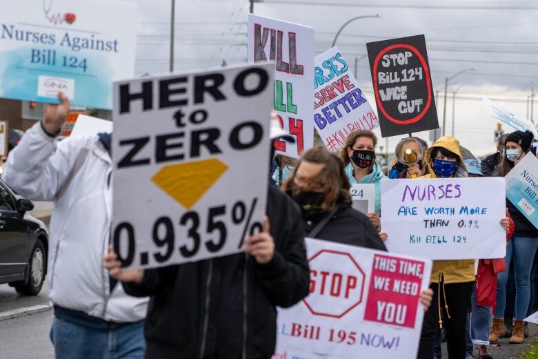 Protestors hold signs saying 