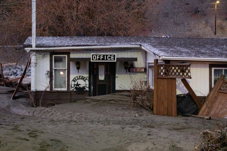 Mud flows surround a small building marked 'Office' on a rainy day.