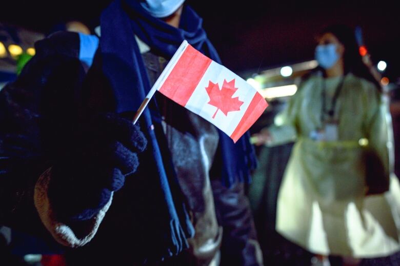 An Afghan refugee holds a small Canadian flag at the St. John's International Airport, on Oct. 26, 2021.  The Afghans at the centre of the lawsuit say they  have been waiting longer. 