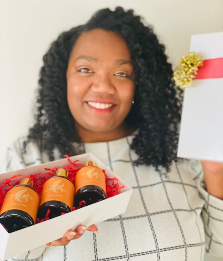 A Black woman with curly hair holding bottles of lotion