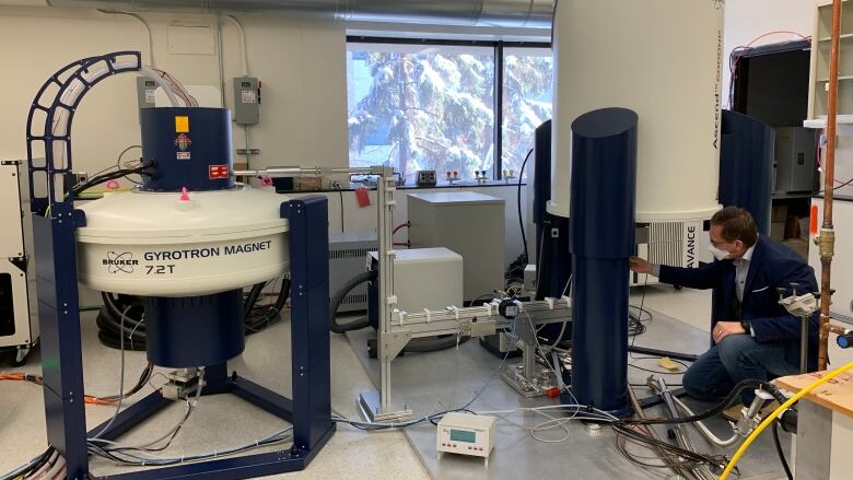 A man leans over an instrument using a superconducting magnet at the University of Alberta.