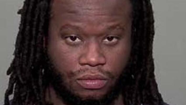 A Black man with long hair in dreads is shown in a mugshot.