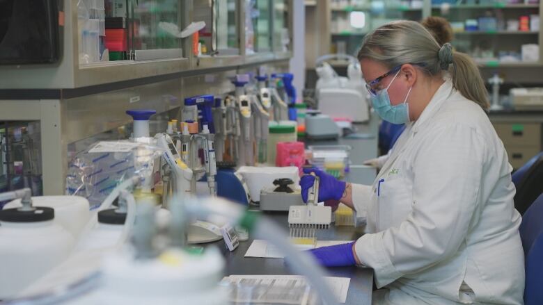 Lab workers in the Medicago facility in Quebec City work with vials.