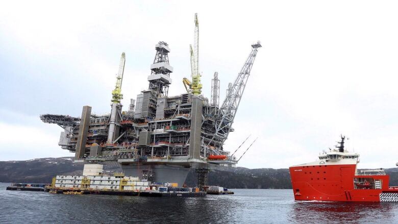 An oil rig and a large ship in the water.