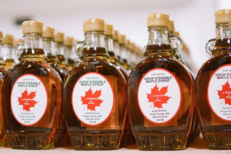 Bottles of maple syrup are pictured on a shelf.