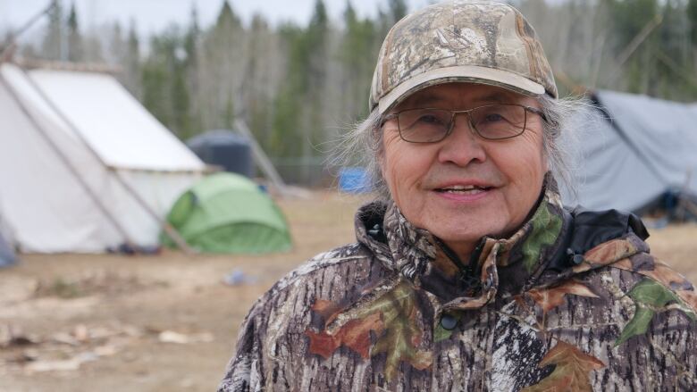 A man stands outside at a campsite.