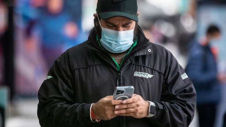 A man is pictured wearing a ball cap and face mask in downtown Vancouver.