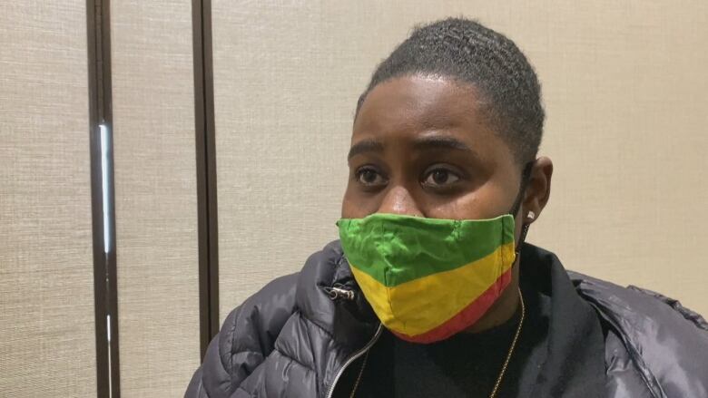 A Black woman wearing a face mask with the flag of Ethiopia/pan African flag