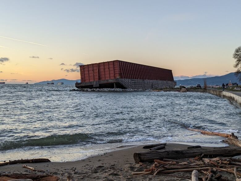 A barge grounded on beach at sunset.