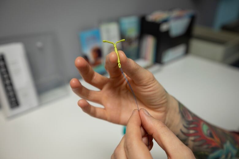 Two hands hold a small yellow device in the shape of a slender Y. 