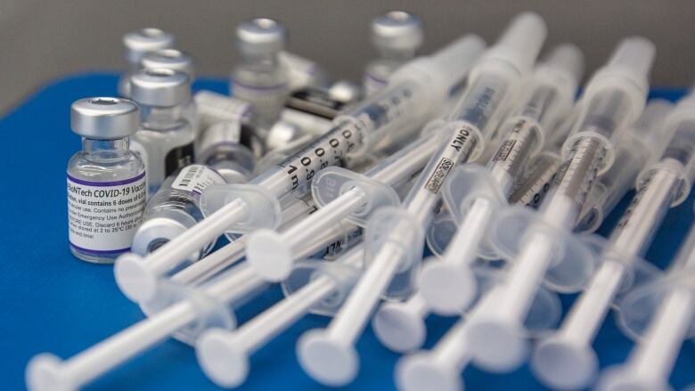 Syringes and vials lay on a blue work surface.