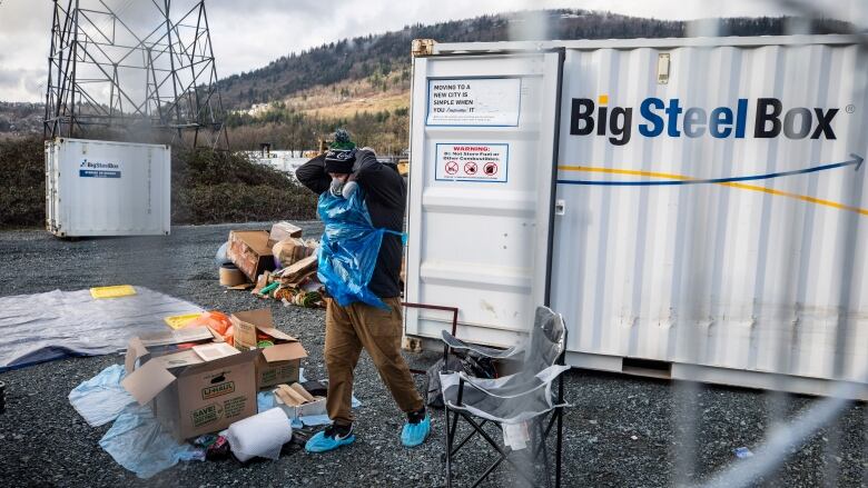 A storage container reads BigSteelBox while a man wearing protective gear cleans out its contents.