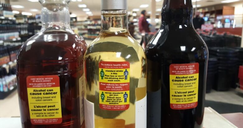 Bottles of alcohol are shown with warning labels that say 