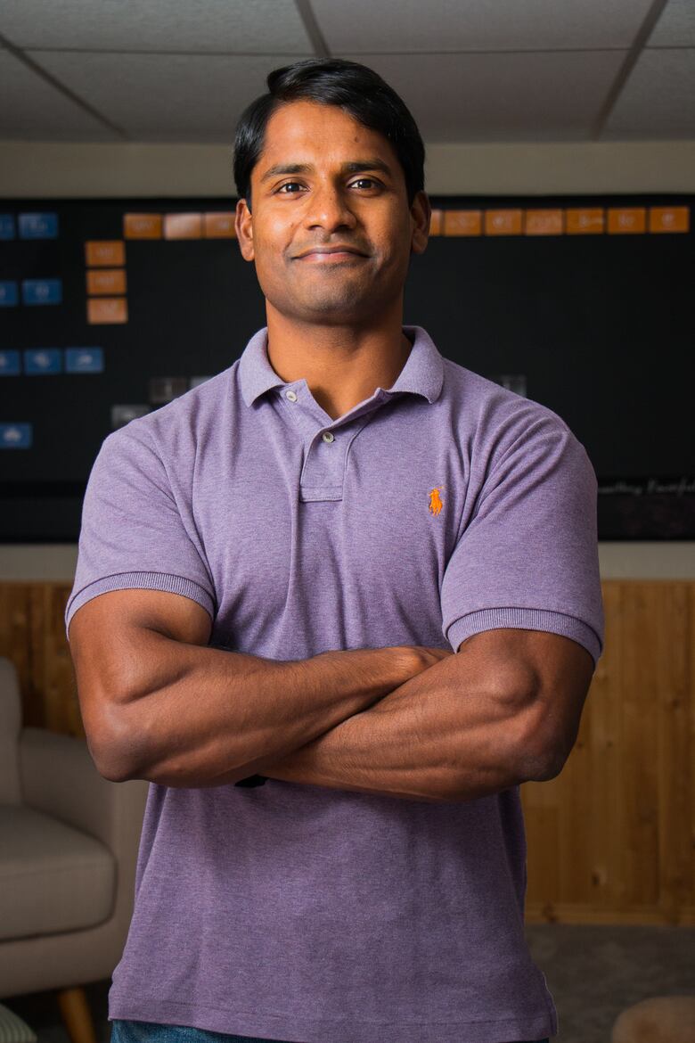 man standing with arms crossed in purple shirt