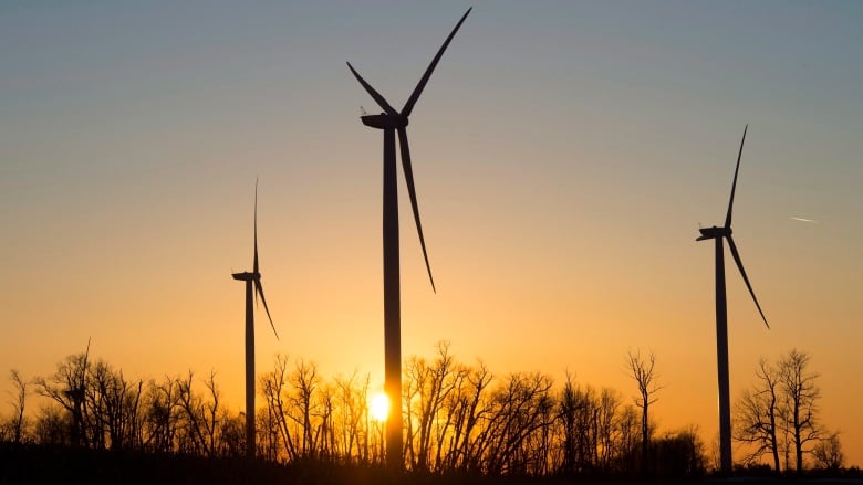 Wind turbines spin in front of the setting sun near Orono, Ont.