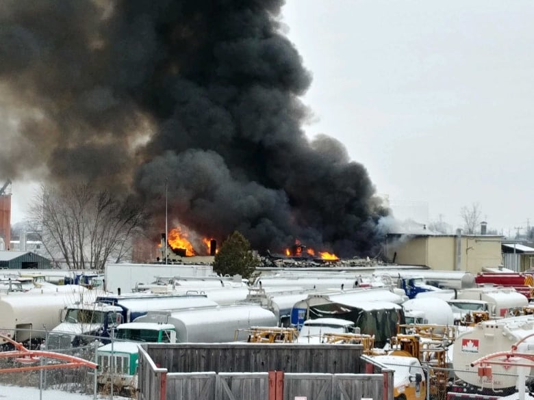 Smoke billows into the air following an explosion in an industrial area in winter.