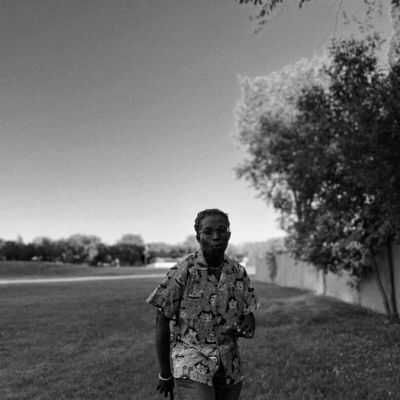 A black & white photo of a Nigerian woman in a Hawaiian shirt dancing 