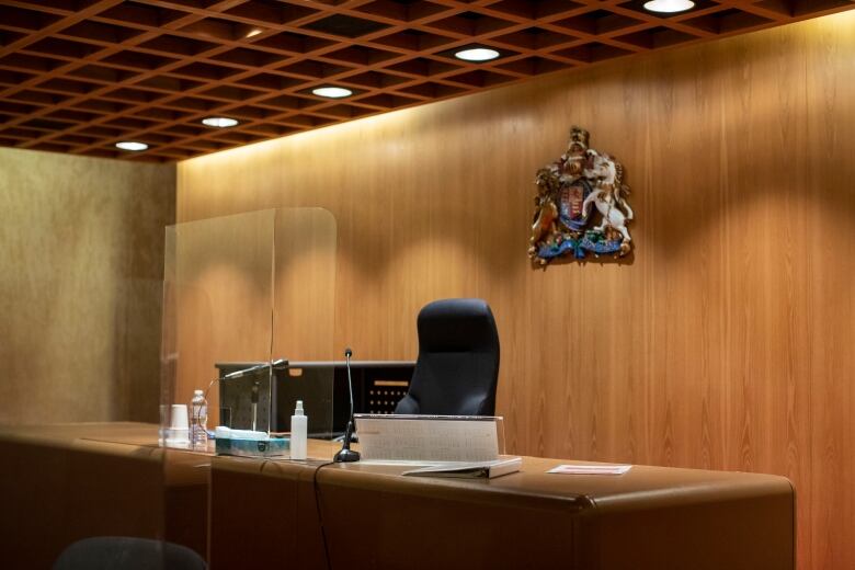 A courtroom interior with a crest of British Columbia behind a judge's desk.