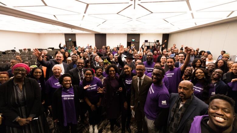 A large group of people wearing purple shirts that read 