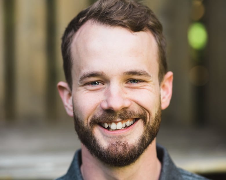 A photo profile of a man smiling directly facing the camera.