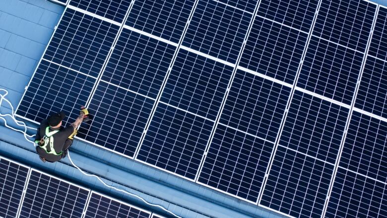 Man installing solar panels on a roof