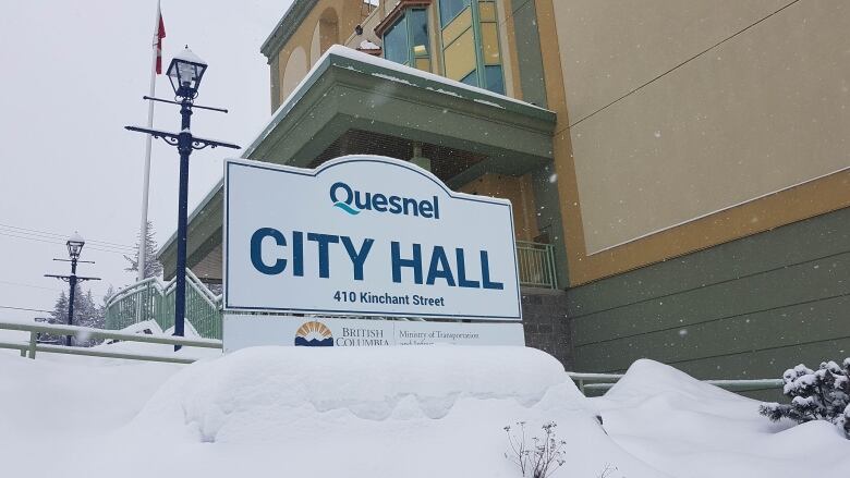 Quesnel City hall sign outside a snowy building.