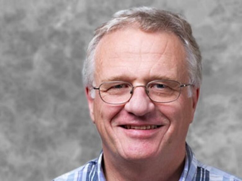 A close-up of a man with glasses and grey hair.