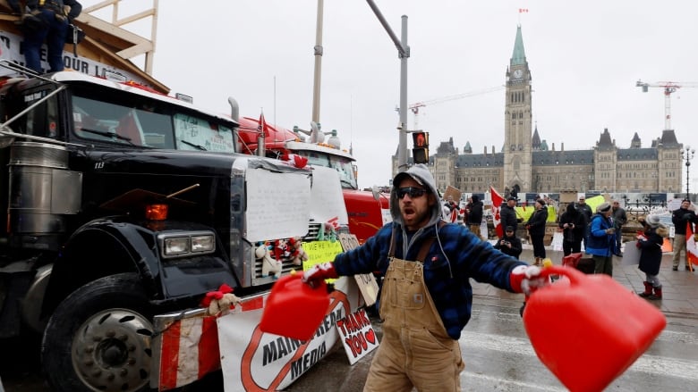 A demonstrator screams and bangs gas canisters together during the ongoing protest in Ottawa Feb. 10, 2022.