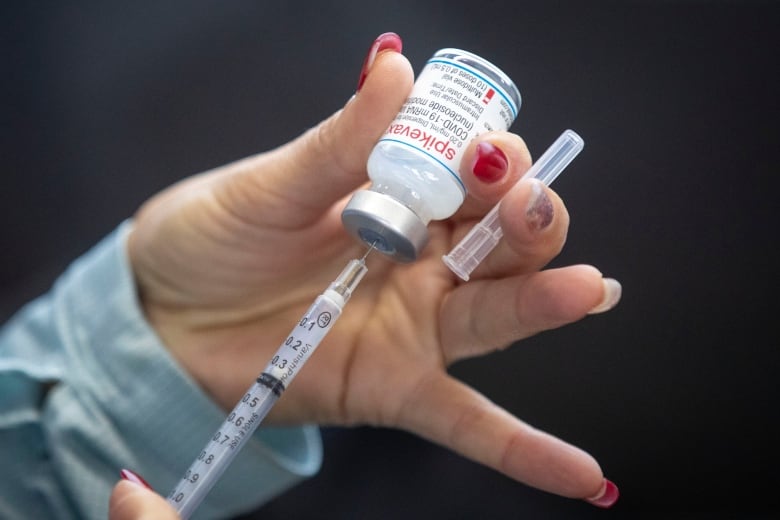 A person draws out a Moderna dose during a drive-through COVID-19 vaccine clinic at St. Lawrence College in Kingston, Ont. 