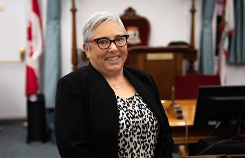 Woman in glasses poses in provincial legislature. 