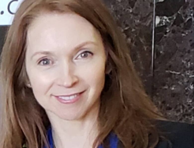 A headshot of a woman with red-brown hair who is smiling. 