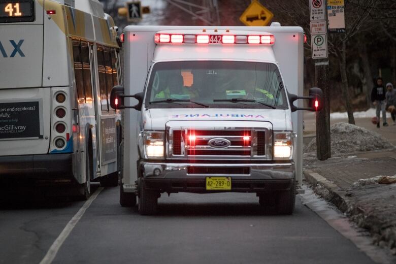 Am ambulance with sirens on busy city street at dusk 