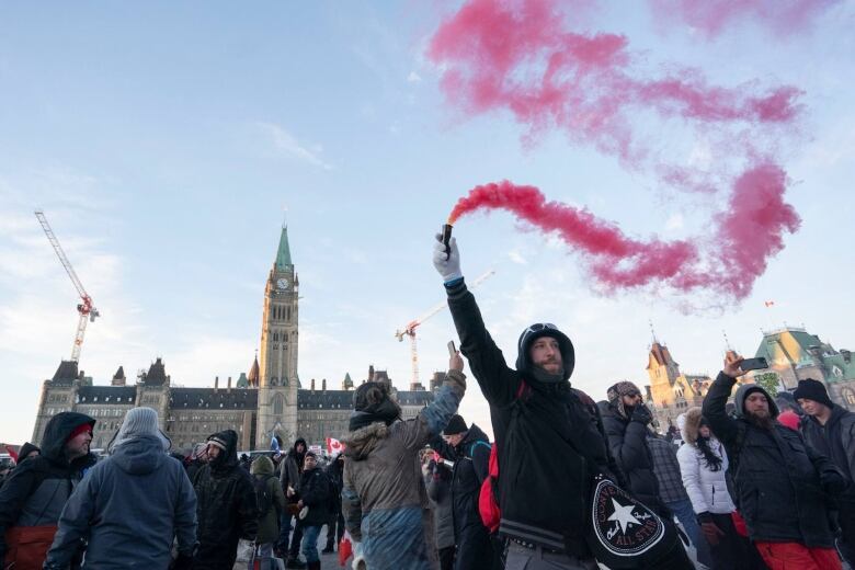 A man waves a can of red smoke in the air outside the parliament buildings in Ottawa.