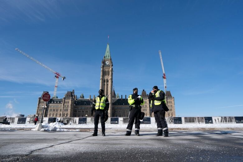 Three officers stand on Parliament Hill.