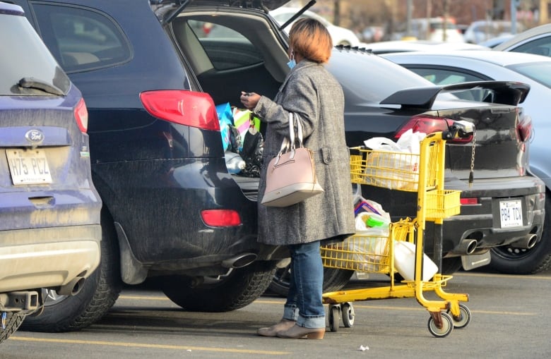 A woman loads groceries into the trunk of her car.