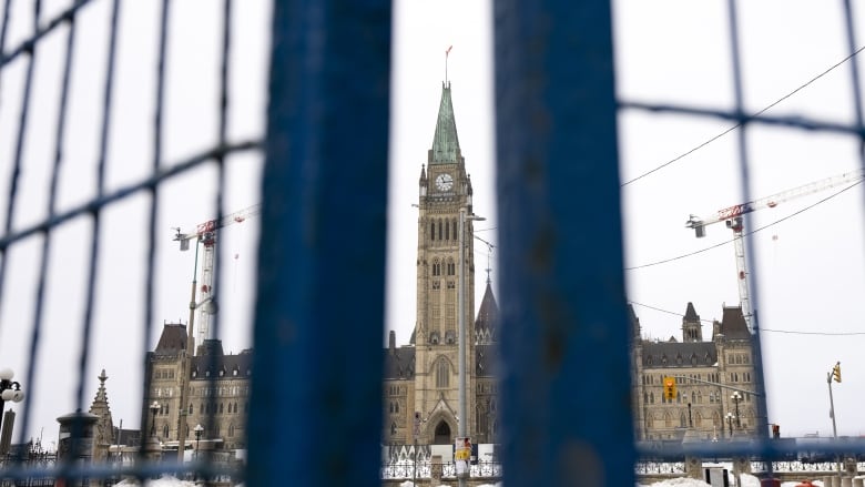 A legislature tower seen between a gap in a temporary fence.